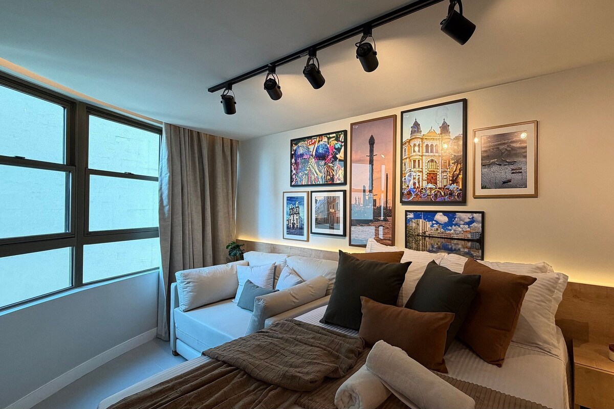 A modern bedroom with a bed, a sofa, and a large window.