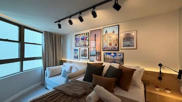 A modern bedroom with a bed, a sofa, and a large window.