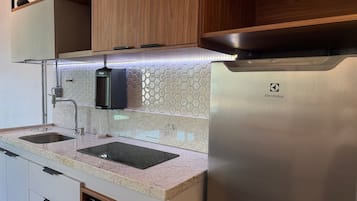 A kitchen with a stainless steel refrigerator, two sinks, a faucet, and a hexagonal tile backsplash.