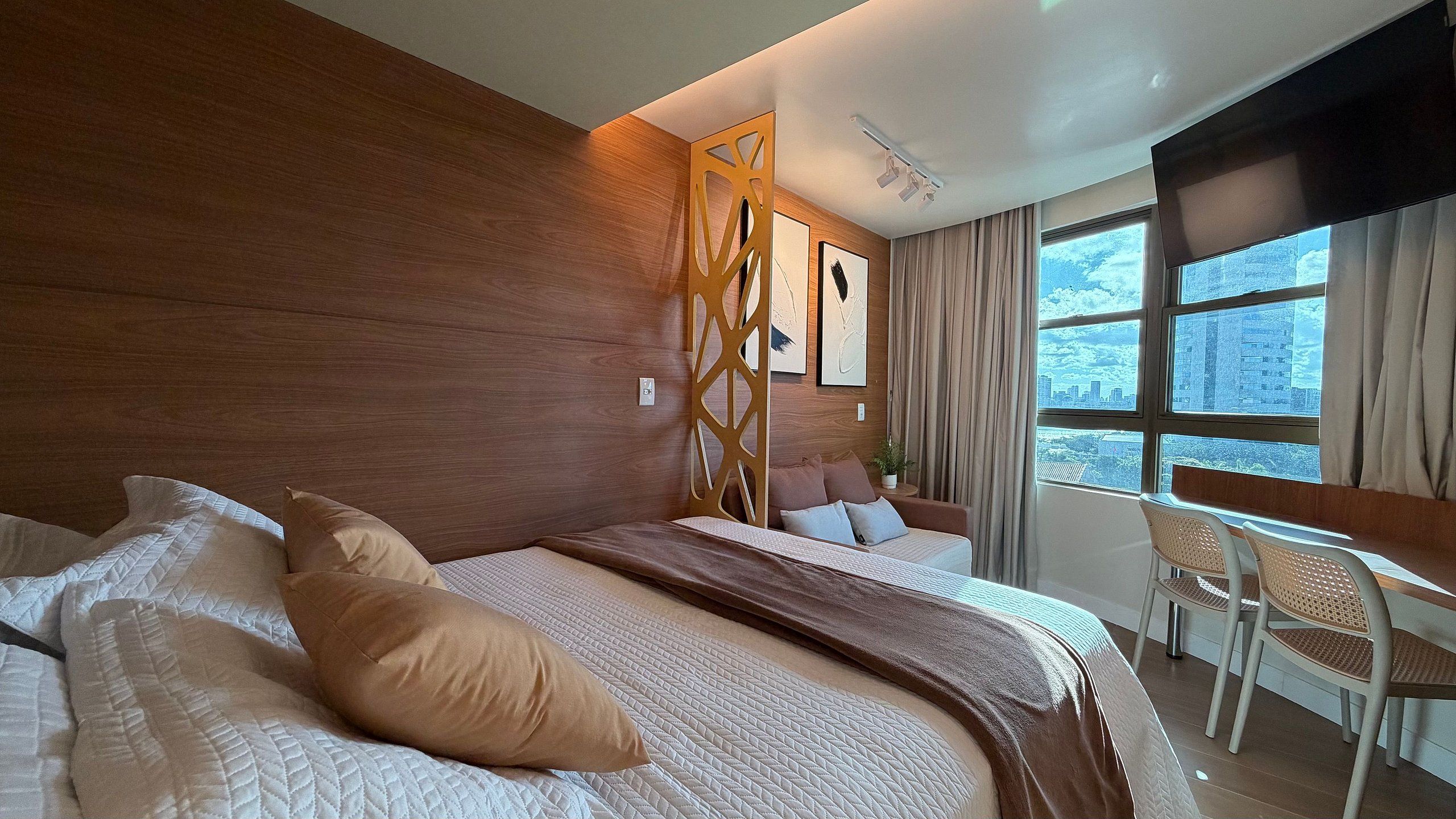 Habitación de hotel moderna con una cama grande, un escritorio y vistas de la ciudad a través de la ventana.