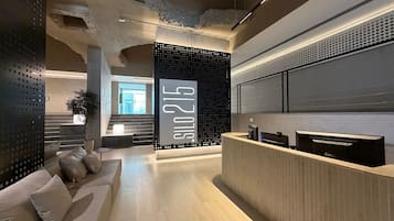 A reception area with a modern design, including a reception desk, seating area, and a large wall with the number '215'.