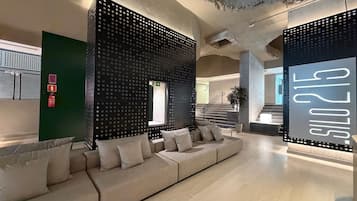 A modern interior with a sectional sofa, a staircase, and a wall with a perforated design.