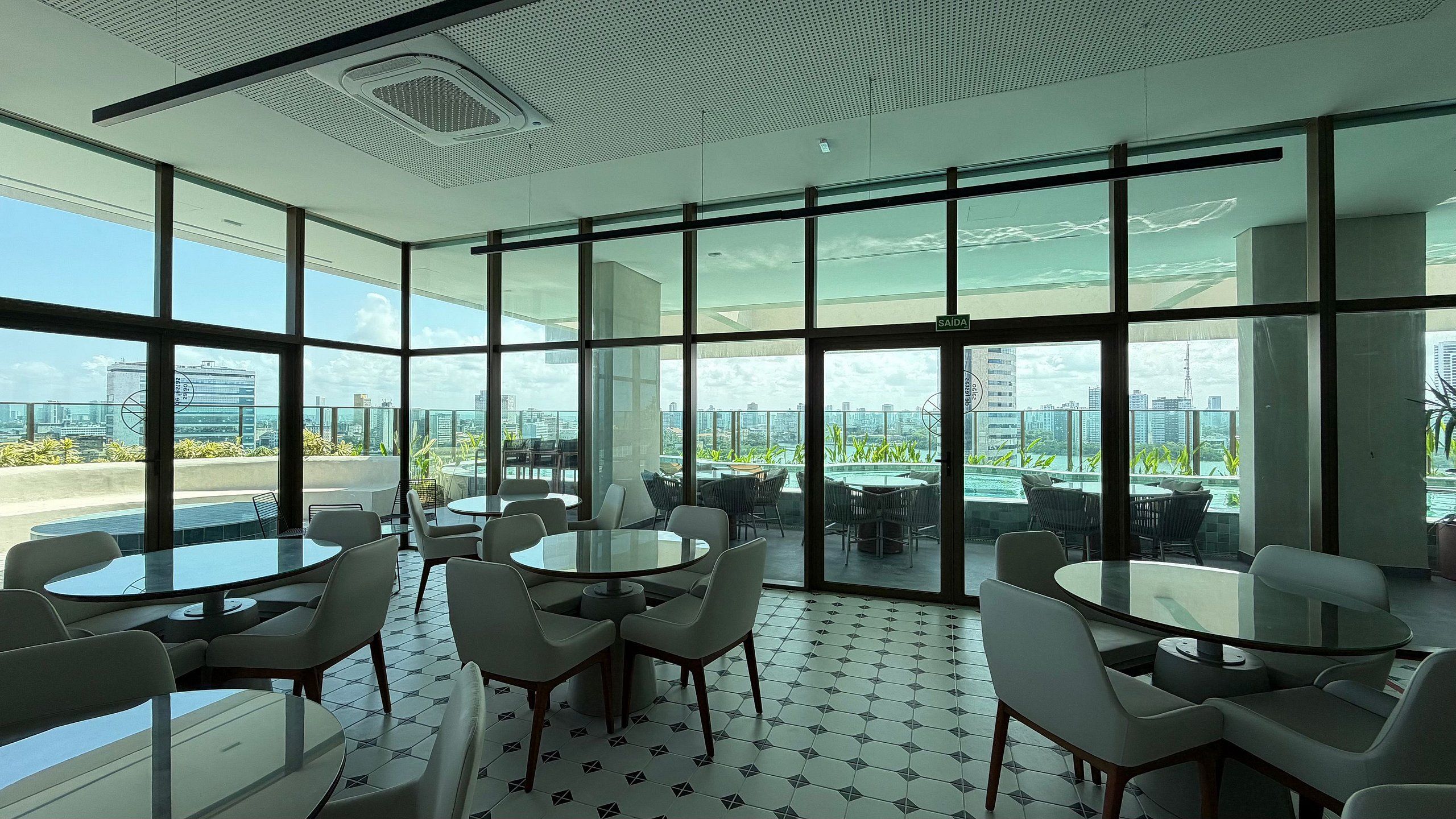 A modern conference room with large windows, round tables, and chairs.