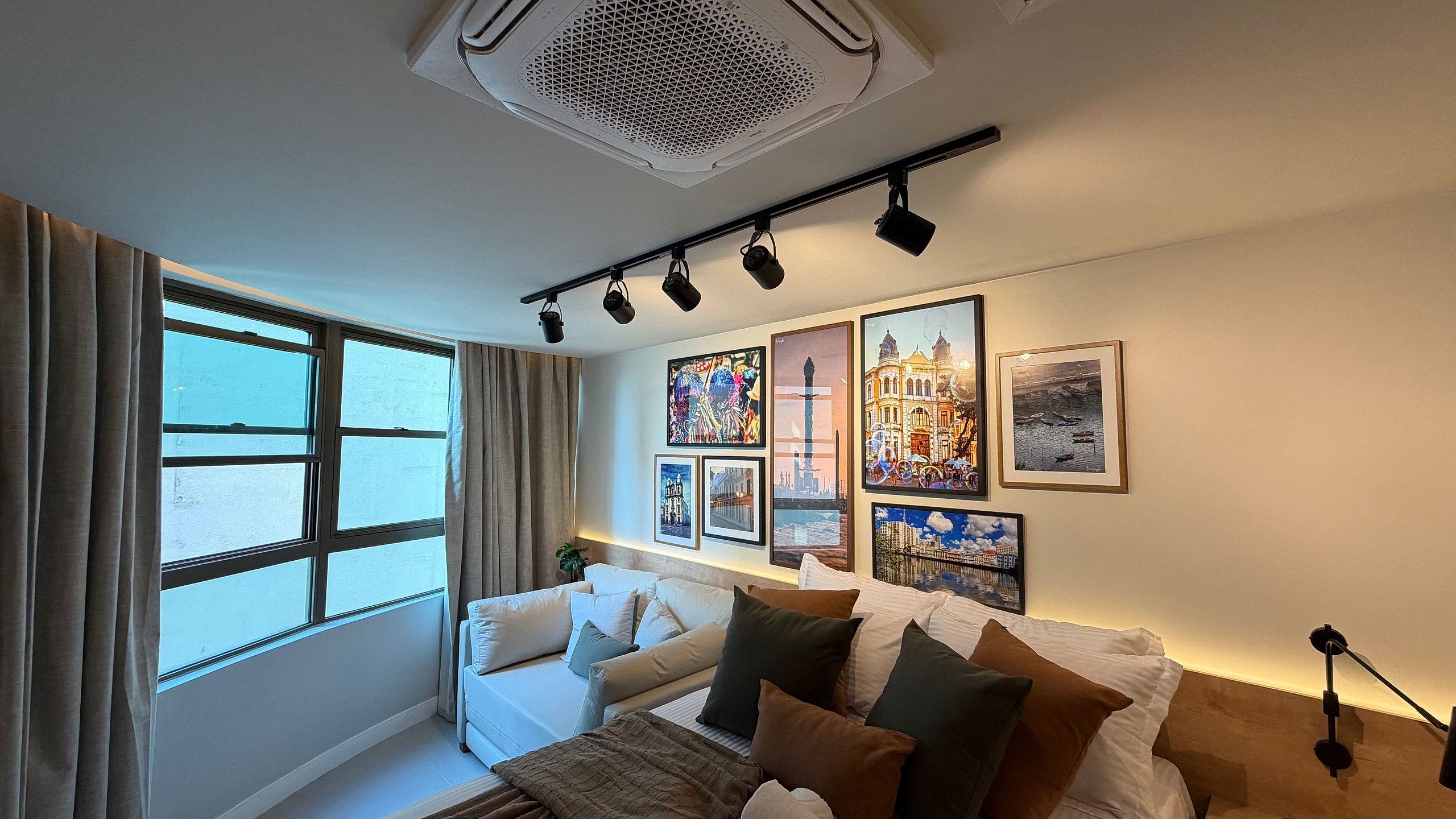 A room with a large window, a sofa, and wall-mounted artwork.