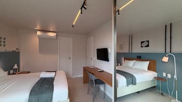 Una habitación de hotel moderna con dos camas, un escritorio, un televisor y un espejo.