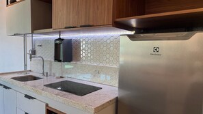 Una cocina con un refrigerador de acero inoxidable, dos fregaderos, un grifo y un salpicadero de azulejos hexagonales.