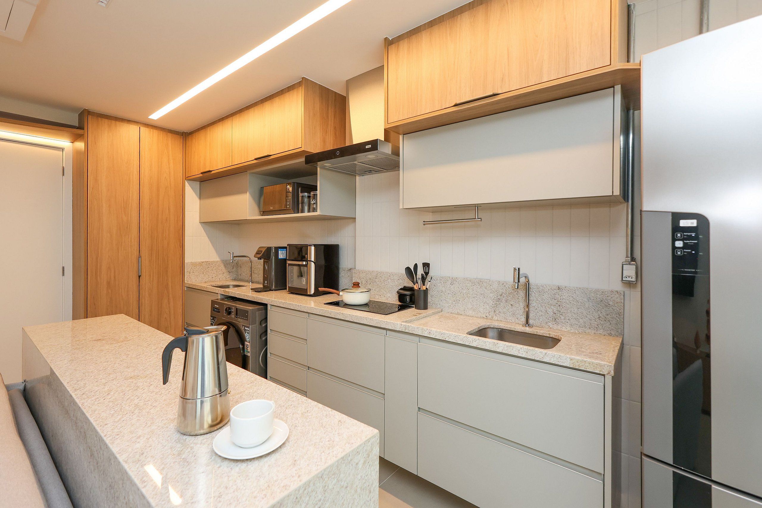 Una cocina moderna con un refrigerador de acero inoxidable, una cafetera y un hervidor sobre la encimera.