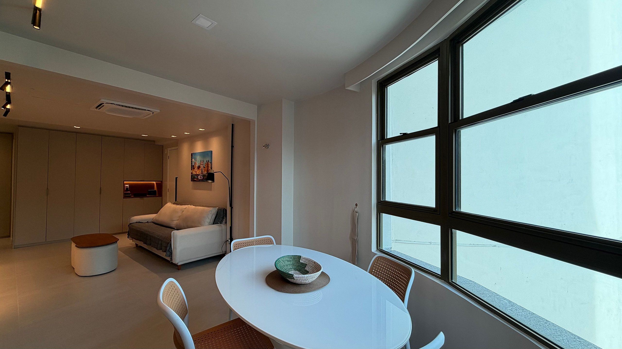 Un interior moderno con una zona de comedor, un sofá y un ventanal grande.