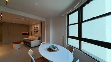 Un interior moderno con una zona de comedor, un sofá y un ventanal grande.