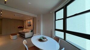 A modern interior with a dining area, a sofa, and a large window.