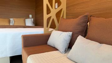 A hotel room with a bed, a brown sofa, and two pillows.