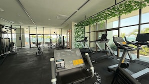 A gym with treadmills, weight machines, and a wall of greenery.