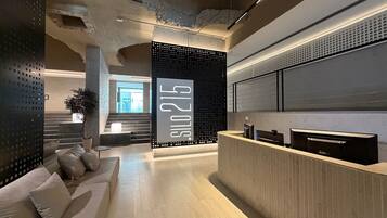 A reception area with a modern design, including a reception desk, seating area, and a large wall with the number '215'.