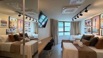 Une chambre d’hôtel avec deux lits, un bureau, un téléviseur à écran plat et des œuvres d’art accrochées aux murs.