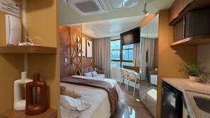 Una camera d'albergo moderna con un letto, un'area ristorazione e una cucina.