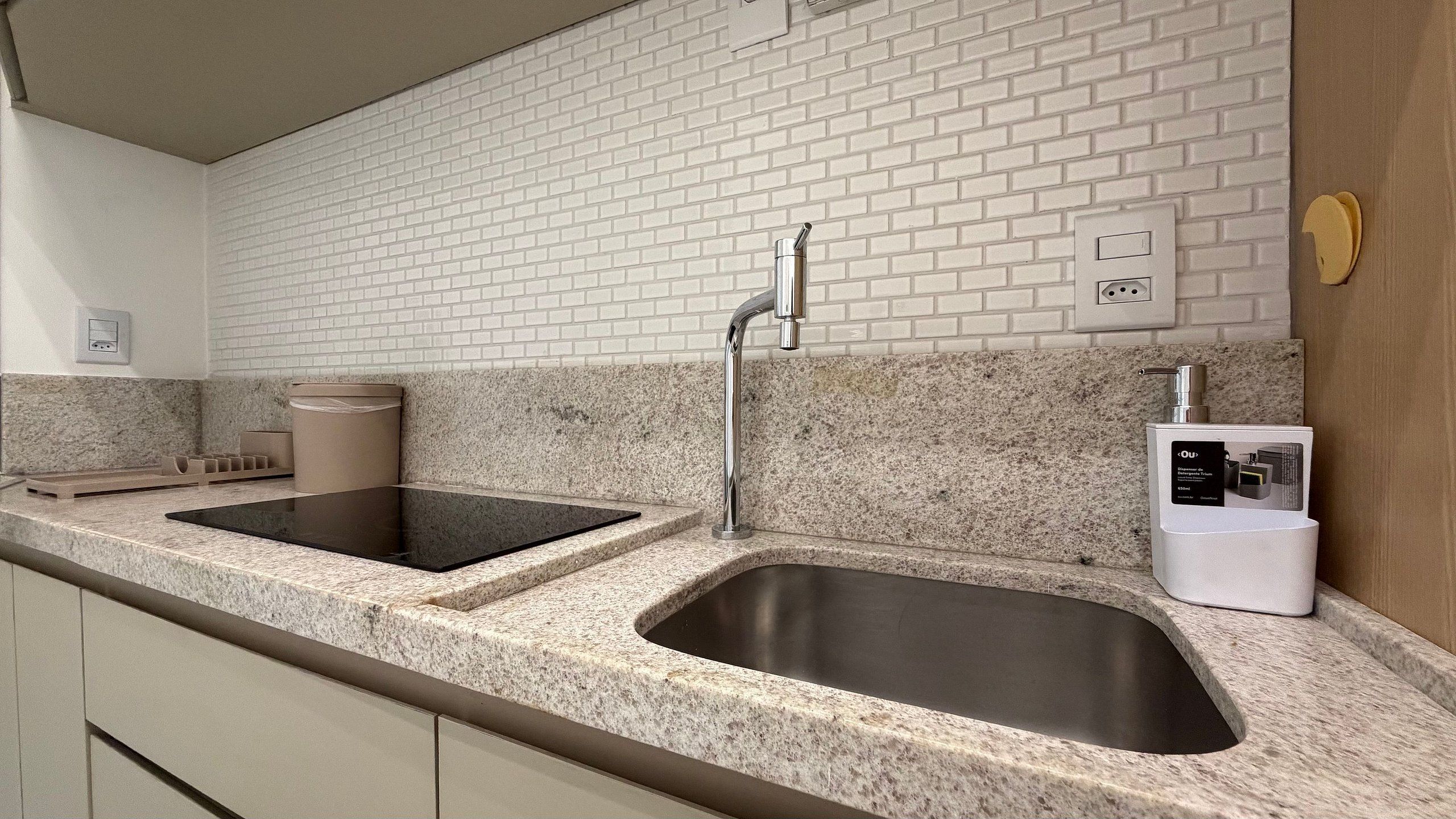 A modern kitchen with granite countertops, stainless steel sinks, and a built-in dishwasher.