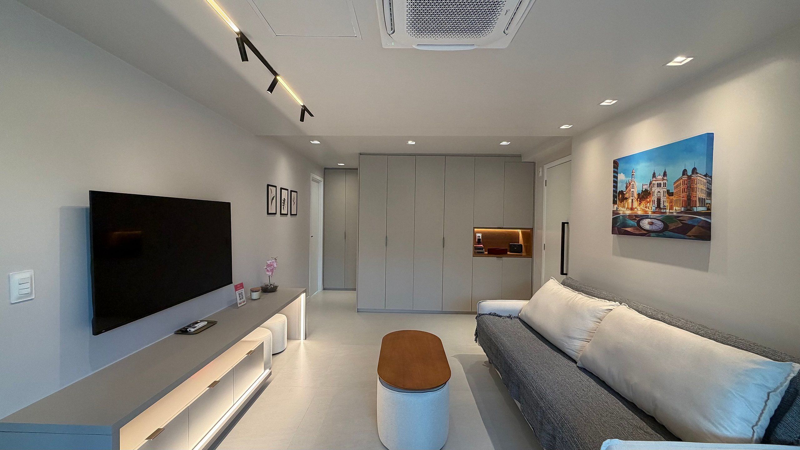 Una sala de estar moderna con una televisi ón de pantalla plana, un sofá, una mesa de centro y un cuadro en la pared.