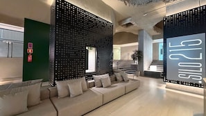 Un interior modern amb un sofà modular, una escala i una paret amb disseny perforat.