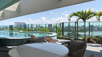 Terraza en la azotea con piscina, zona de estar y vistas a la ciudad.