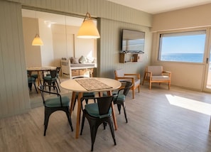 A modern living room with a round dining table, chairs, a sofa, and a television.
