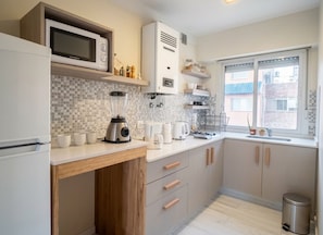 A modern kitchen with a built-in microwave, coffee maker, and a window with a view of the outside.