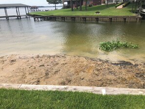 A waterfront property with a dock extending into a body of water, a grassy area, and a building in the background. - 4-bedroom house with AC in charming Crosby (Crosby)