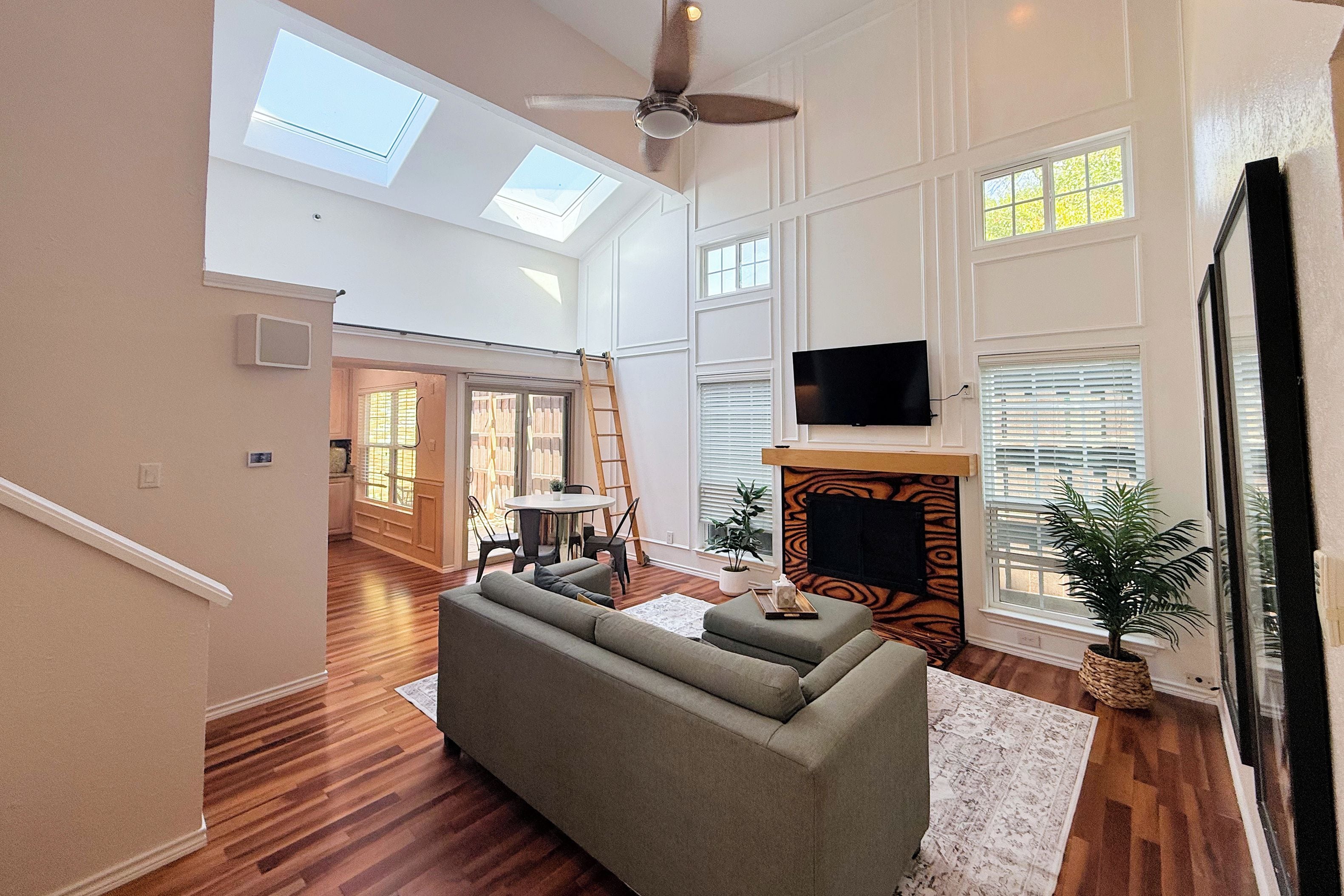 A spacious living room with a sofa, a fireplace, a television, and a ceiling fan.