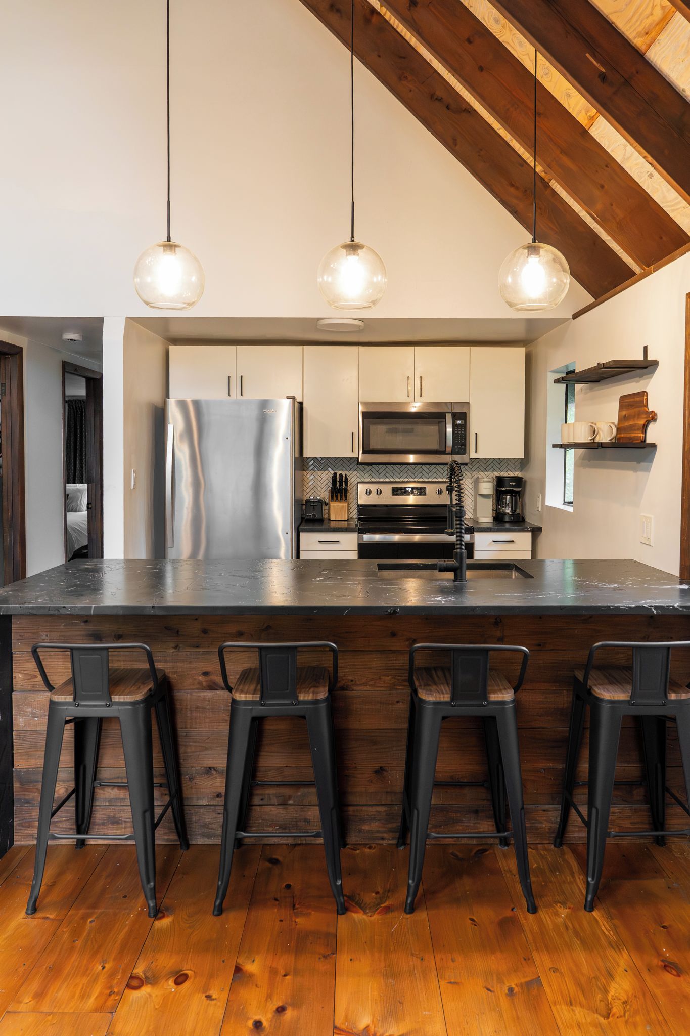 A modern kitchen with a large island, stainless steel appliances, and bar stools.