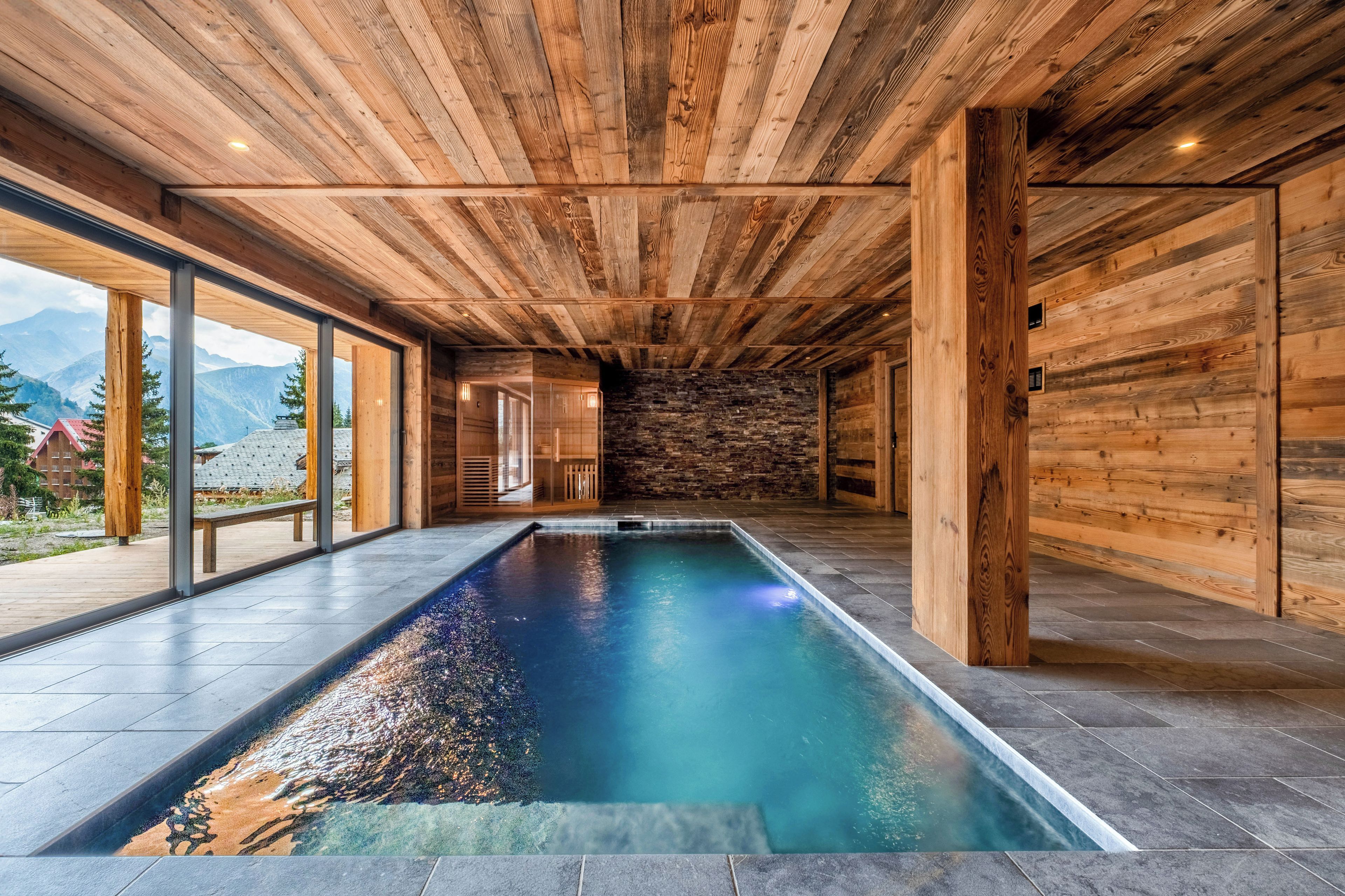 Una piscina interior moderna con vigas de madera en el techo y paredes de piedra.