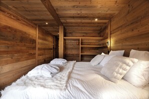 A wooden cabin interior with a bed, white bedding, and a wooden ceiling. - Exceptional Chalet – Luxury & Mountain Views (Les Deux Alpes)