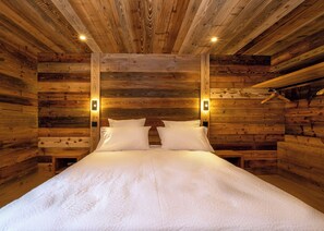 Une pièce aménagée comme un chalet en bois, avec un lit, deux tables de chevet et des appliques murales.