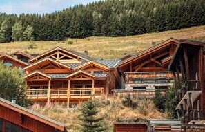 Eine Holzhütte mit geneigtem Dach, umgeben von einem bewaldeten Hang.
