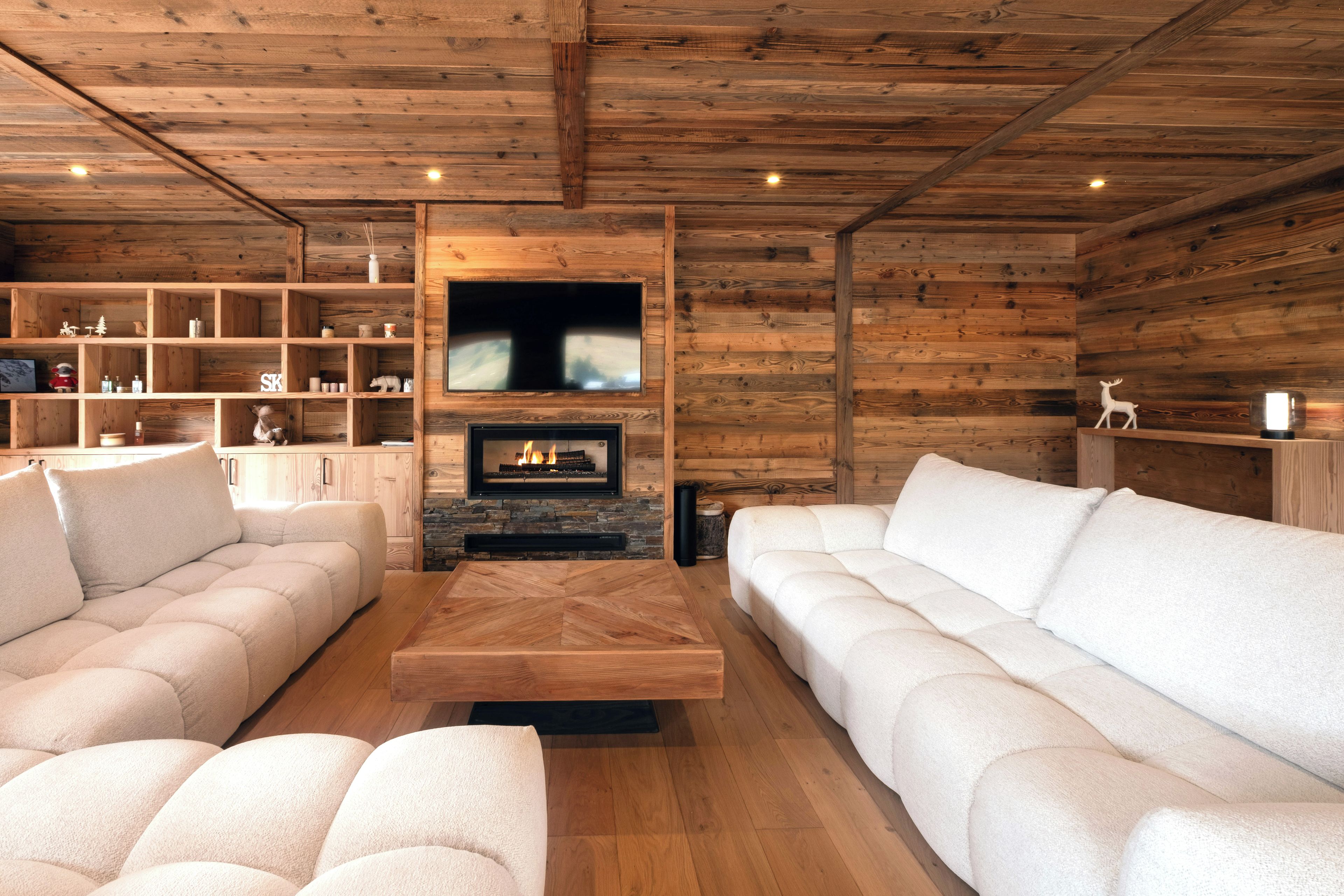 Una sala de estar acogedora con chimenea, paredes de madera y un televisor montado arriba.