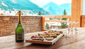 Ein Holztisch mit einer Champagnerflasche, einer Wurstplatte und Gläsern.