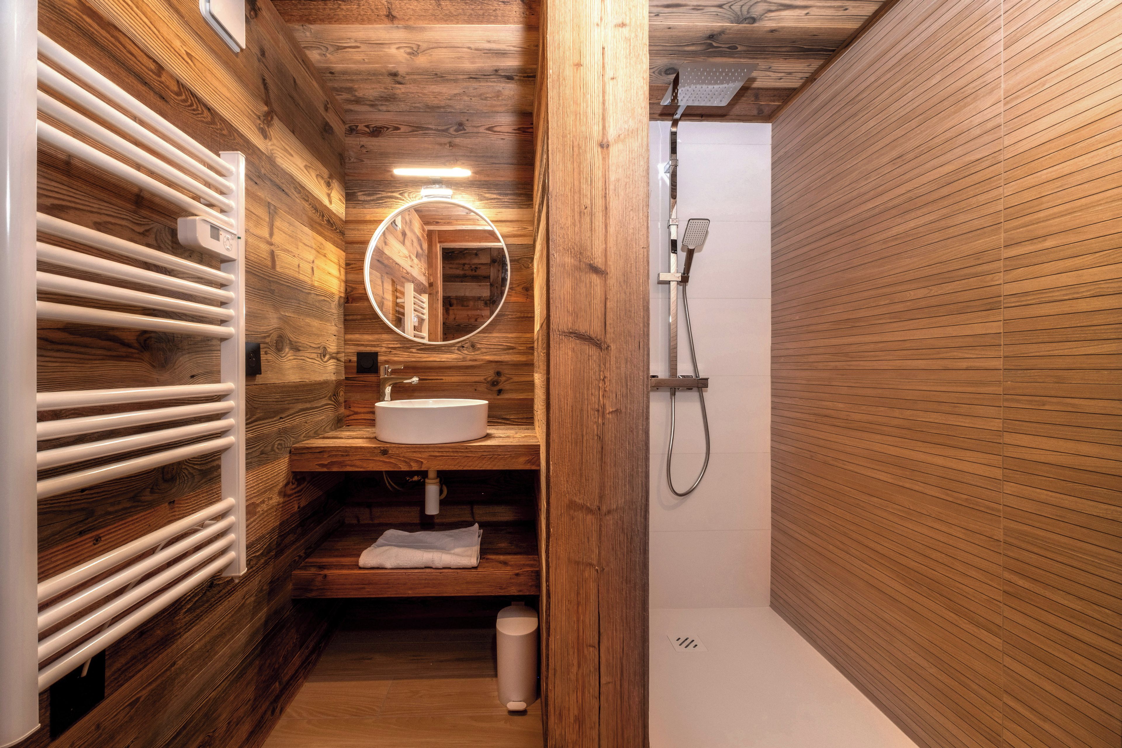 Un interior de madera con un lavabo integrado, un espejo y una ducha.