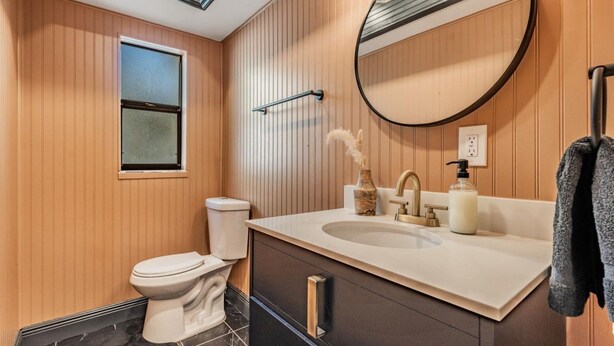 A modern bathroom with a toilet, sink, mirror, and towel rack. - Tampa Lake House – Dock, Pool Table & Putt Green (Tampa)