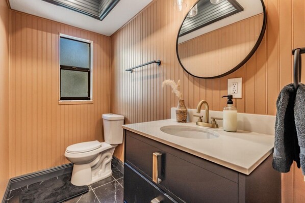 A modern bathroom with a toilet, sink, mirror, and towel rack.