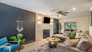 A modern living room with a sofa, a coffee table, a blue chair, and a fireplace. - Tampa Lake House – Dock, Pool Table & Putt Green (Tampa)