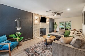 A modern living room with a sofa, a coffee table, a blue chair, and a fireplace.