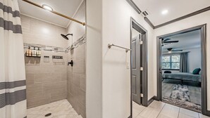 A modern bathroom with a shower, toilet, and a glass door leading to a bedroom. - Tampa Lake House – Dock, Pool Table & Putt Green (Tampa)