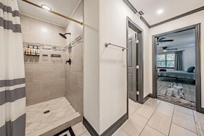 A modern bathroom with a shower, toilet, and a glass door leading to a bedroom.