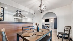 A modern dining area with a wooden table, woven placemats, and a chandelier. - Tampa Lake House – Dock, Pool Table & Putt Green (Tampa)