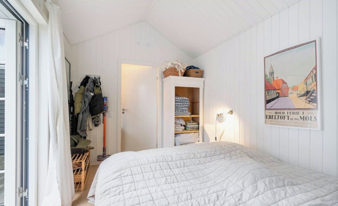 A bedroom with a bed, a wardrobe, and a door leading to a balcony.