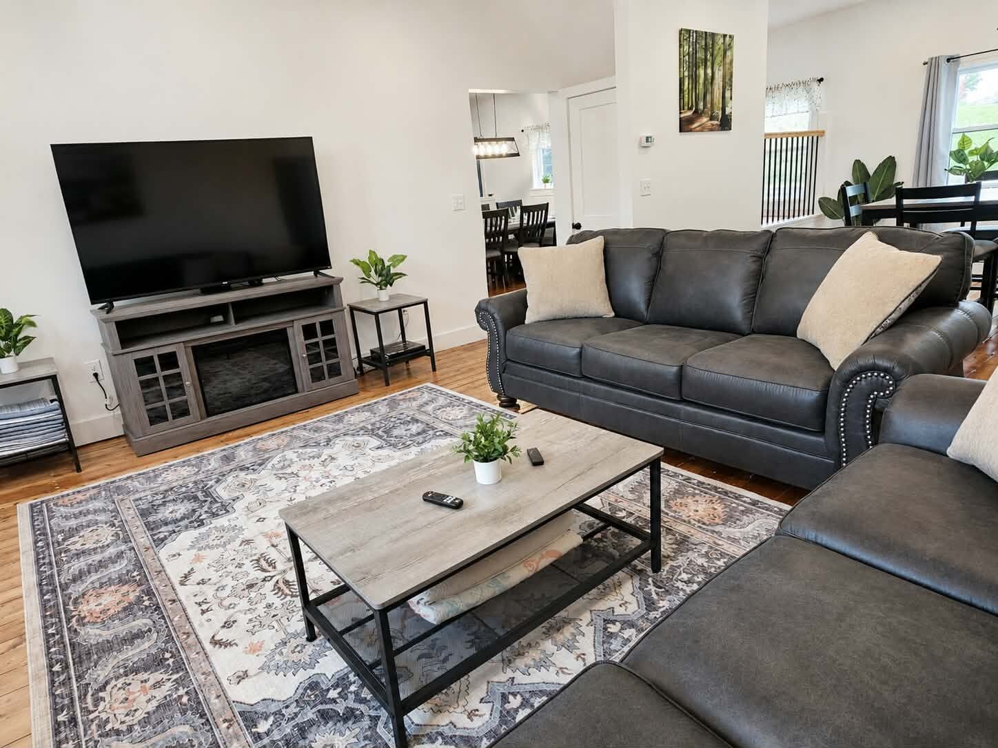 Un salon moderne avec un téléviseur à écran plat, un canapé en cuir, une table basse et un tapis à motifs.