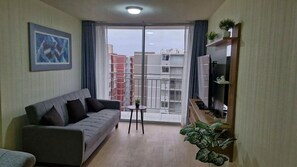 A modern living room with a grey sofa, a small round table, and a potted plant. - Minimal Living Apartment - Near the Airport, perfect for Your Stay (Lima)