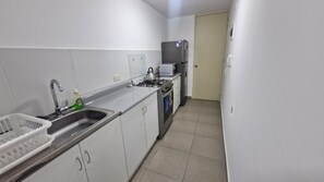 A compact kitchen with a sink, stove, microwave, and refrigerator. - Minimal Living Apartment - Near the Airport, perfect for Your Stay (Lima)