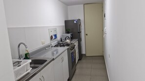 A compact kitchen with a sink, stove, and refrigerator. - Minimal Living Apartment - Near the Airport, perfect for Your Stay (Lima)