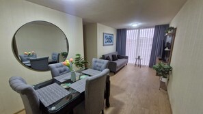 A modern living room with a dining area, a large round mirror, and a sofa. - Minimal Living Apartment - Near the Airport, perfect for Your Stay (Lima)