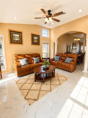 A spacious living room with a sectional sofa, a coffee table, and a ceiling fan.