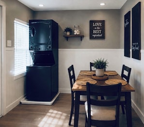 A compact kitchen with a built-in microwave, a dining table with four chairs, and decorative wall art. - Near Airport, Golf & Medical Center - California King Bed (San Antonio)